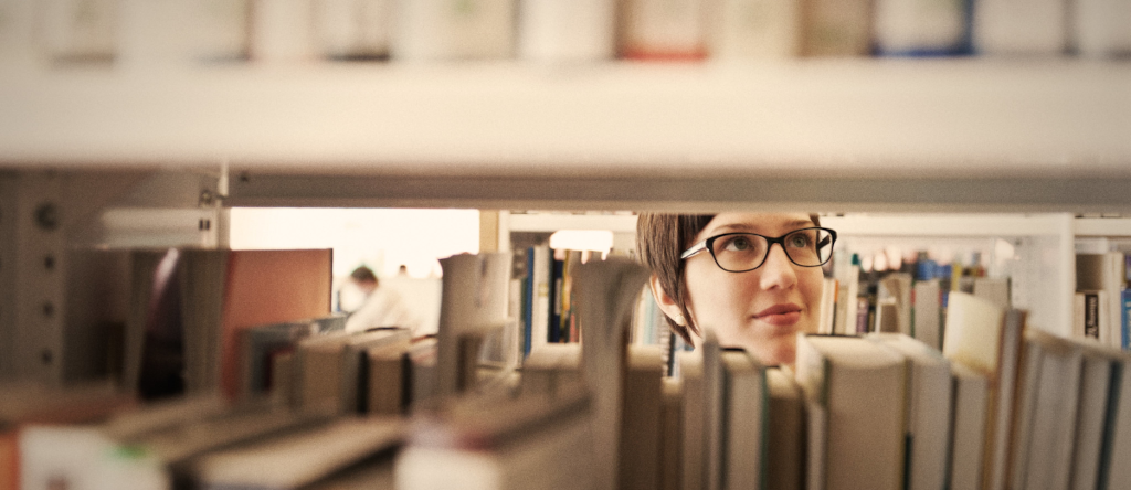Una mujer mirando los estantes de una biblioteca