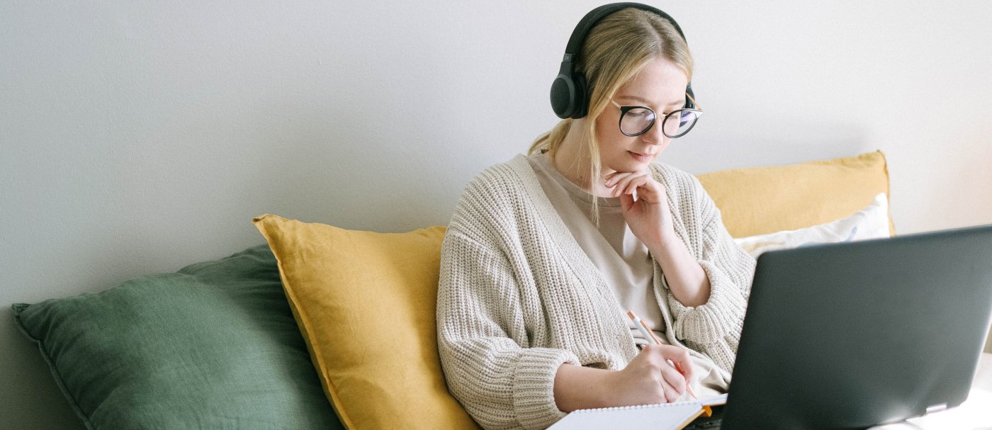 Chica con un portátil, una libreta y auriculares